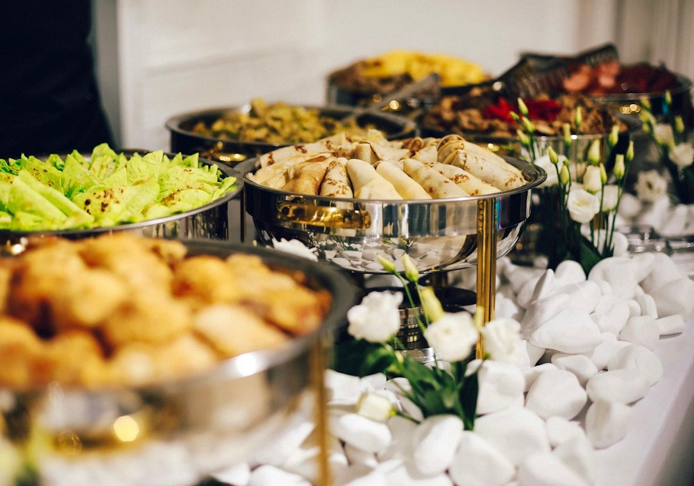 Buffet table lined with silver chafing dishes at a catered event
