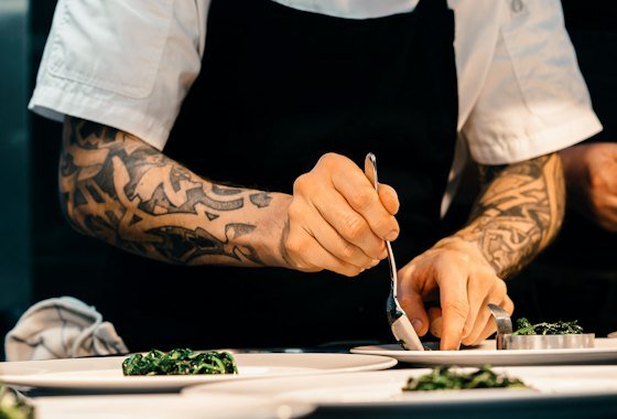 Chef plating a course by hand in the kitchen